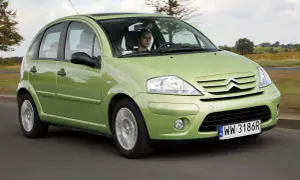 Zielony Citroen C3 z 2003 roku jedzie po drodze, za kierownicą młody mężczyzna.
