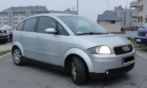 Srebrny Audi A2 1.4 benzyna zaparkowany przed blokami.