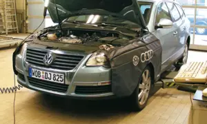 Passat B6 2.0 TDI 140KM w warsztacie, z otwartą maską i osłoną na błotniku. Obok klawiatura i myszka.