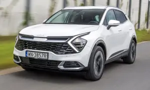 Biały Kia Sportage w ruchu. Wiele osób szuka kia sportage opinie przed zakupem.