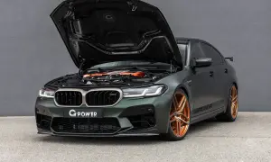 Mocarny BMW M5 G Power z otwartą maską, prezentujący pomarańczowy silnik i miedziane felgi.