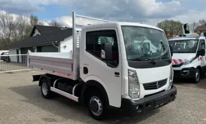Biały Renault Maxity z otwartą skrzynią ładunkową stoi na placu.