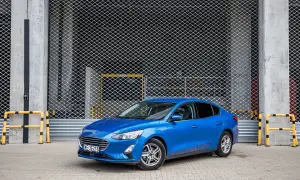 Niebieski Ford Focus 1.0 EcoBoost stoi przed metalową bramą.