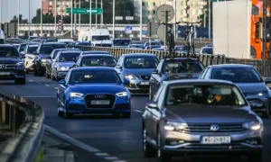 Korek uliczny, różne rodzaje samochodów osobowych i dostawczych, w tym luksusowe marki i auta z rowerami na dachu.