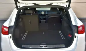 Otwarty bagażnik białej Kia Optima kombi. Wnętrze jest puste, gotowe na podróż.