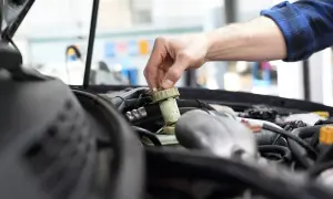 Ręka mechanika dokręca korek zbiorniczka płynu hamulcowego. Zapobiega to mandatom, od kiedy kara za spóźniony przegląd jest surowa.