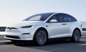 Biały Tesla X w ruchu. Kierowca w okularach przeciwsłonecznych. Sprawdź aktualną tesla x cena i możliwości tego SUV-a.