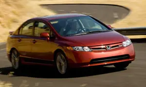 Czerwony Honda Civic Si zgrabnie pokonuje zakręt na pustynnej drodze.