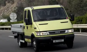 Żółty Iveco Daily 3 z podwójną kabiną i skrzynią ładunkową jedzie po drodze.