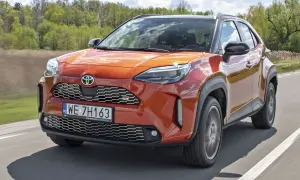 Pomarańczowy Toyota Yaris GR Sport na drodze. Wiele pozytywnych toyota yaris opinie potwierdza jego sportowy charakter i atrakcyjny wygląd.