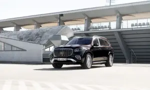 Elegancki, czarny Mercedes GLS Maybach z chromowanymi detalami i charakterystycznym grillem, zaparkowany na tle nowoczesnej architektury stadionu.