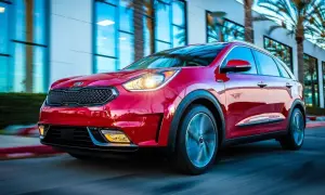 Czerwony Kia Niro w ruchu. Choć auto prezentuje się świetnie, warto pamiętać o jego potencjalnych wadach, takich jak ograniczona moc czy nieco twarde zawieszenie.