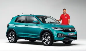 Mężczyzna w czerwonej koszulce stoi obok turkusowego Volkswagena T-Cross, który przekracza wymiary miejskiego auta.