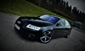 Czarny Audi A6 C6 3.0 TDI Quattro S-line na tle zielonego wzgórza i lasu.