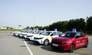 Rząd białych samochodów nauki jazdy z literą "L" na dachu i czerwony Opel z napisem "AUTOMAT" na placu manewrowym. Sprawdź, jaki jest prawo jazdy b+e koszt.