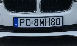 Biały samochód z tablicą rejestracyjną PO-8MH80.