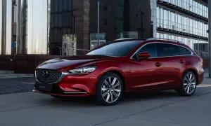 Czerwone kombi Mazda 6 na tle nowoczesnego budynku. Poznaj jej wymiary i możliwości.