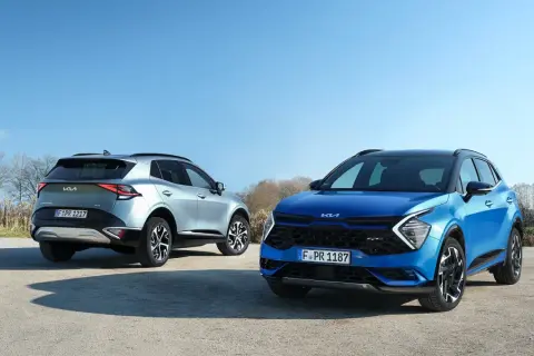 Dwa Kia Sportage, niebieski i srebrny, prezentują swoje imponujące kia sportage wymiary na tle błękitnego nieba.