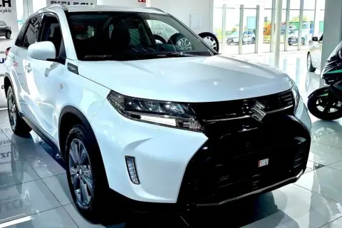 Biały Suzuki Vitara Hybrid błyszczy w salonie, gotowy na miejskie przygody.