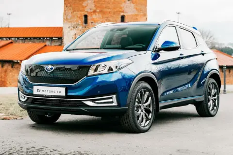 Błękitny SUV EV Motors.eu na tle ceglanych budowli. Jego nowoczesny design i ekologiczne serce przyciągają wzrok.