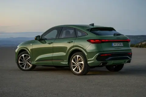 Zielony q5 audi z elegancką linią dachu, zaparkowany na pustkowiu o zachodzie słońca.