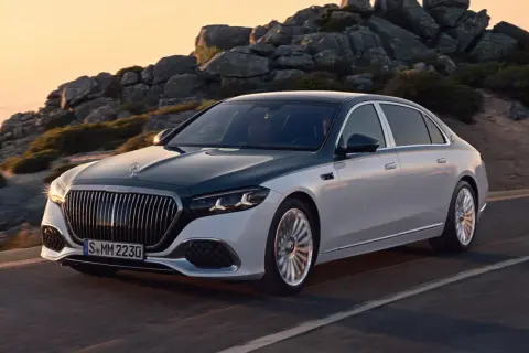 Elegancki, dwukolorowy Mercedes-Maybach sunie po górskiej drodze o zachodzie słońca.