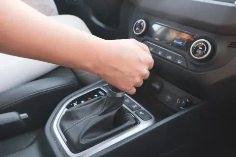 Dłoń zmienia bieg w automatycznej skrzyni biegów.