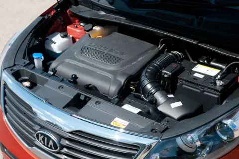 Silnik CRDi w Kia Sportage 2013. Widoczna pokrywa silnika, akumulator, płyny i elementy układu dolotowego.