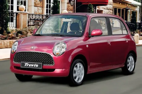 Czerwony Daihatsu Trevis z charakterystycznym grillem i okrągłymi światłami mija elegancki budynek.