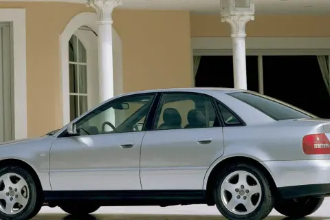 Srebrne Audi A4 B5 stoi przed eleganckim budynkiem z kolumnami.