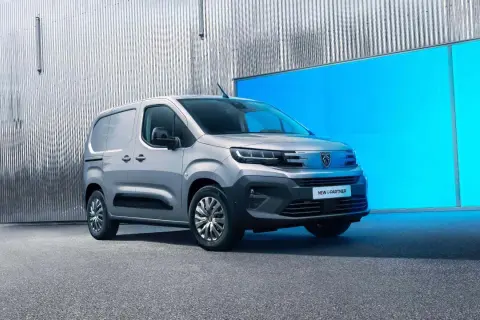 Nowy Peugeot e-Partner, srebrny van, stoi przed błyszczącą, falistą ścianą i jaskrawoniebieskim panelem.