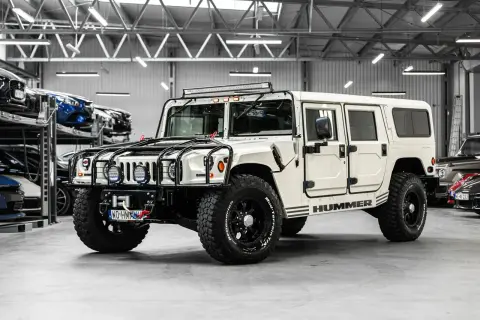 Biały Hummer H1 z potężnymi oponami i dodatkowym oświetleniem na dachu, gotowy na każdą przygodę.