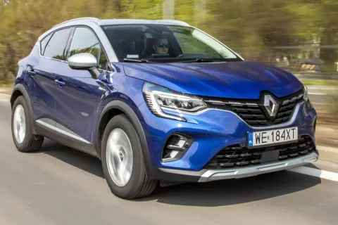Błękitny Renault Captur 2019 pędzi po drodze, kierowca w okularach obserwuje trasę.