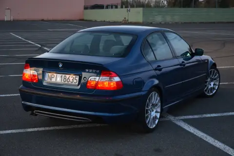 Granatowe BMW E46 330d na parkingu. Wiele pozytywnych opinii o tym modelu, szczególnie o jego silniku.