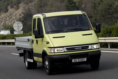 Żółty Iveco Daily 3 z podwójną kabiną i skrzynią ładunkową jedzie po drodze.