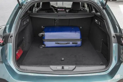 Bagażnik Peugeot 308 SW gotowy na wakacje. W środku niebieska walizka i apteczka.