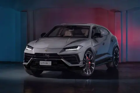 Szary Lamborghini Urus S z czerwonymi zaciskami hamulcowymi stoi w studiu z niebieskim i czerwonym oświetleniem.