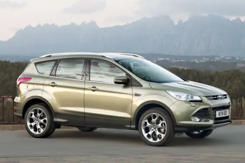 Złoty Ford Kuga na tle górskich krajobrazów. Wiele osób chwali ten model, a jego opinie są pozytywne.