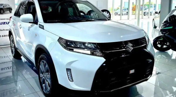 Biały Suzuki Vitara Hybrid błyszczy w salonie, gotowy na miejskie przygody.