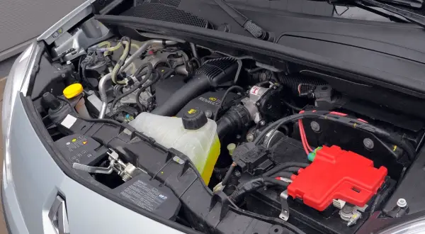 Silnik Renault Kangoo 2 z widocznym zbiorniczkiem płynu chłodniczego, akumulatorem i czerwonymi osłonami.