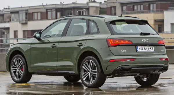 Zielony Audi Q5 na mokrym parkingu. Sprawdź aktualną audi q5 cena i wyposażenie.