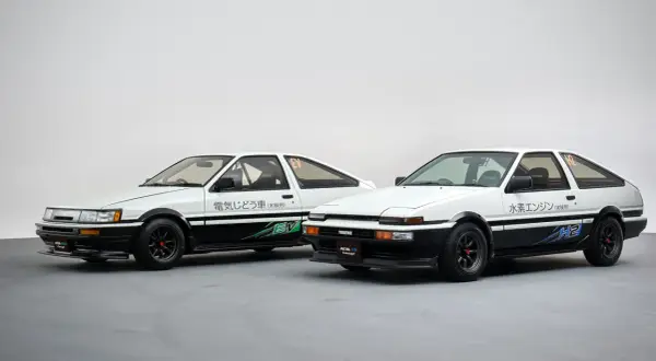 Dwa białe coupe ae86: jeden z napędem elektrycznym (EV), drugi z silnikiem wodorowym (H2).