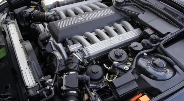 Silnik V12 BMW z widocznymi kolektorami dolotowymi i pokrywą z logo marki.