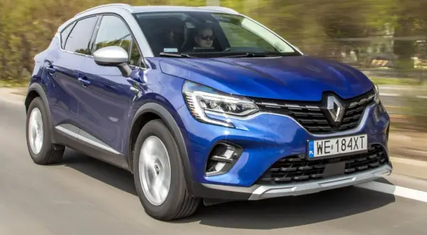 Błękitny Renault Captur 2019 pędzi po drodze, kierowca w okularach obserwuje trasę.