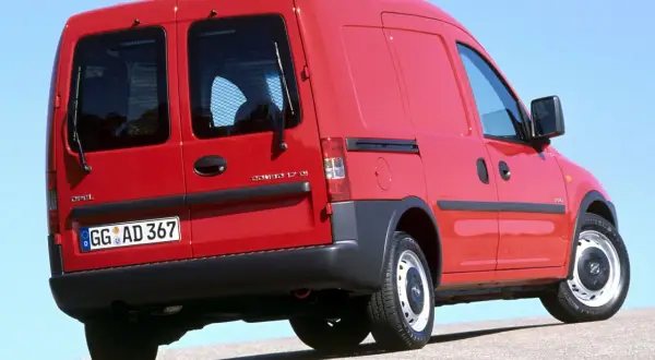 Czerwony Opel Combo C z przyciemnianymi tylnymi szybami i kratką ochronną.