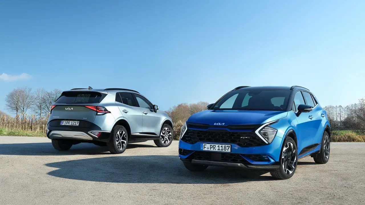 Dwa Kia Sportage, niebieski i srebrny, prezentują swoje imponujące kia sportage wymiary na tle błękitnego nieba.