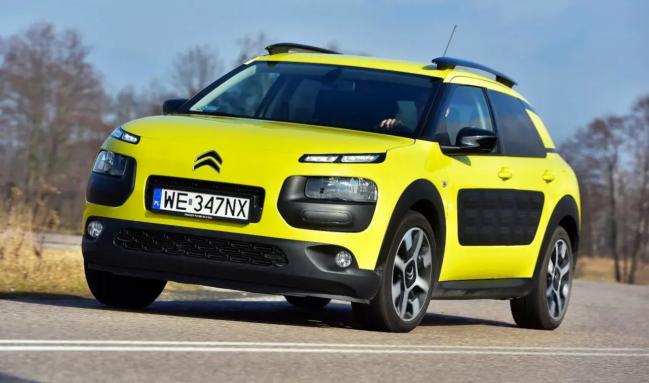 Żółty Citroen C4 Cactus na drodze. Kierowca testuje auto, zbierając pozytywne opinie o jego komforcie i oryginalnym wyglądzie.
