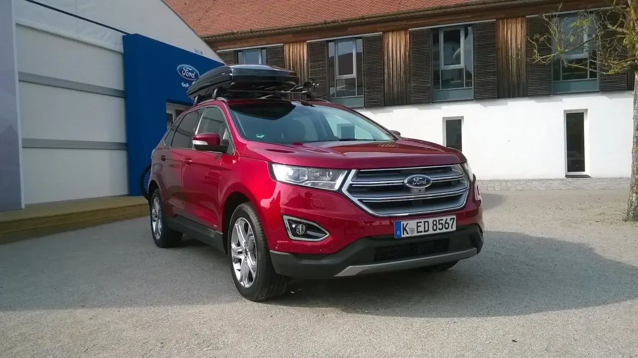 Czerwony Ford Edge z boxem dachowym, idealny na rodzinne wyjazdy. Sprawdź jego imponujące ford edge wymiary!