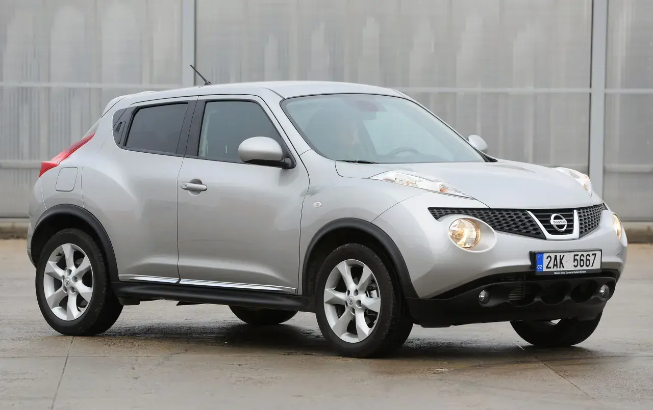 Srebrny Nissan Juke, często chwalony w nissan juke opinie, prezentuje się dynamicznie na tle nowoczesnej architektury.