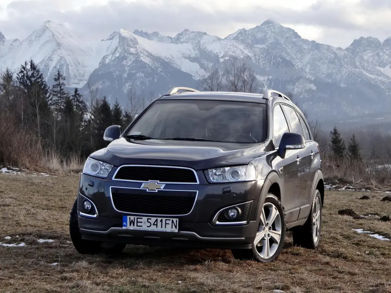 Chevrolet Captiva na tle górskich szczytów. Wiele osób szuka chevrolet captiva opinie, by sprawdzić, czy ten SUV sprawdzi się w trudnym terenie.